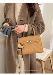 Brown woven texture handbag with metal lock and plush charm for autumn commute