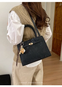 Détail du sac à main rétro en cuir noir avec pendentif de baseball et fermoir doré