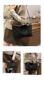 Detail showing the black matte tote with brown leather straps and adjustable shoulder strap