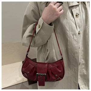 Detail of burgundy pleated crescent bag with vintage buckles and silver metal studs
