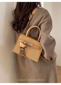 Detail of retro leather and woven small square bag with Hello Kitty charm on long strap
