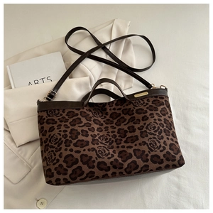 Detail of leopard print tote with rose patterns, brown leather trim and golden metal plate