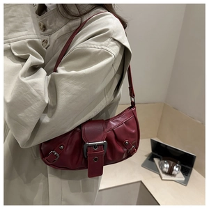 Detail of dark red motorcycle style shoulder bag with metallic buckles and ruching
