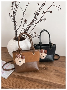 Close-up of a suede and leather patchwork bucket bag with a cute plush bear pendant