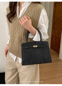 Détail du sac à main en cuir texturé noir avec fermoir tournant doré de style rétro