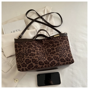 Detail of leopard and rose print tote bag featuring a gold nameplate and brown handles