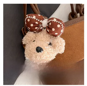 Detail of cute plush bear charm with polka dot bow on a brown leather bucket bag