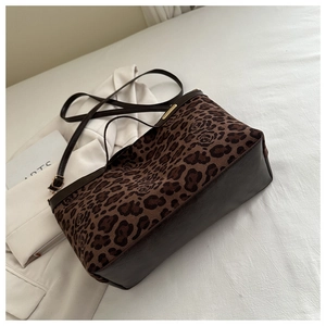 Detail of leopard and rose pattern texture with brown leather handles on tote bag