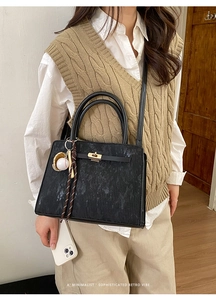 Close-up of retro black crossbody bag with gold clasp and unique baseball charm detail