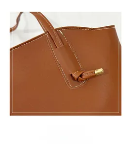 Detail der braunen Leder-Tote mit weißen Kontrastnähten und verknotetem Kordelzug-Design