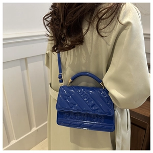 Detail of royal blue patent leather handbag with FASHION embossing and quilted texture