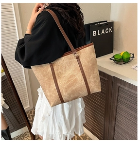 Side view of large khaki tote bag with dark brown leather straps on model shoulder