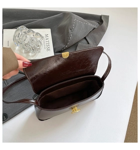 Detailed interior of vintage dark brown baguette bag with golden metal twist lock closure