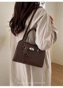 Detail showing dark brown litchi grain texture and silver metal twist lock on the bag