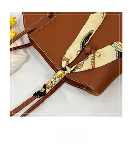 Detailansicht der dunkelbraunen Ledertasche mit bedrucktem Seidenschal am Griff und Dekor