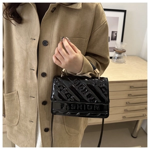 Close-up of black patent leather bag with embossed FASHION lettering and metal handle