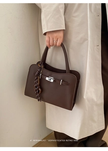 Macro shot of dark brown pebbled leather texture and silver twist lock on top handle bag