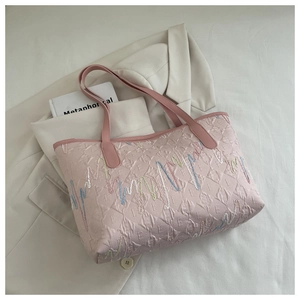 Detail of pink quilted tote bag with F-letter logo pattern and colorful embroidery accents
