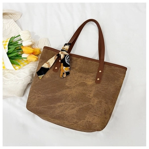 Detail view of brown canvas tote bag with leather straps and decorative silk scarf wrap