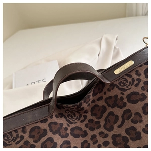Detail of leopard print suede texture and gold logo plaque on a brown fashion tote bag