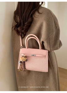 Detail of pink patchwork crossbody bag featuring woven texture and cute cat charm decoration