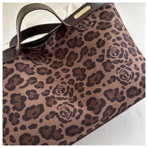 Close-up of leopard and rose pattern suede handbag with dark brown leather handle