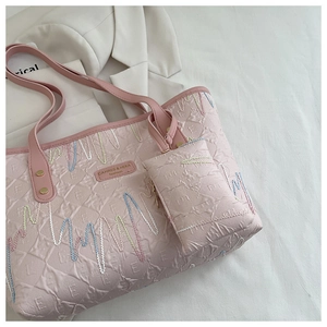 Macro detail of pink tote bag with wavy embroidery and mini coin purse attachment