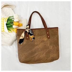 Close-up of brown vintage tote bag with metal rivets and decorative printed silk scarf