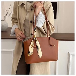 Close-up of brown faux leather tote bag with elegant silk scarf detail and smooth texture