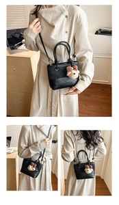 Detail einer Mini-Beuteltasche mit Canvas-Nähten, verstellbarem Gurt und Bären-Anhänger