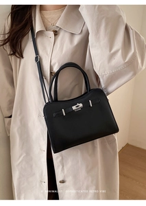 Minimalist black leather handbag featuring silver twist lock and crossbody strap detail