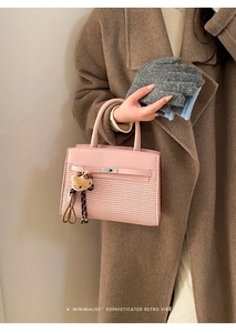 Detail of pink woven crossbody bag with silver twist lock and leopard plush charm