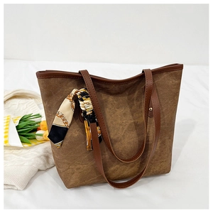 Detail of dark brown suede tote bag featuring a decorative chain-print silk scarf handle