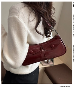 Détail du sac bandoulière en cuir bordeaux avec double poche avant et bandoulière chaîne