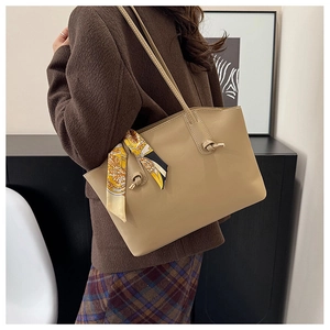 Beige tote bag with patterned silk scarf shown in a stylish over-the-shoulder lifestyle view