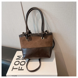 Detail of a brown patchwork bucket bag featuring suede and leather textures on a book