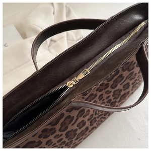 Detail of the high-quality gold metal zipper and brown leather trim on leopard tote bag