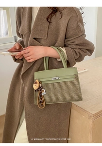 Detail of green leather and straw woven Kelly bag with silver lock and cat charm