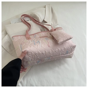 Detailed macro view of pink quilted tote bag with colorful embroidery and letter patterns