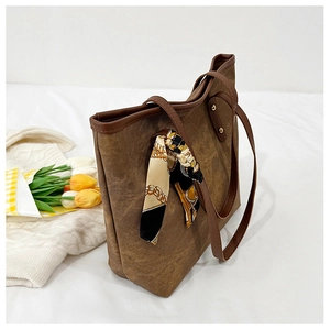 Detail of vintage brown tote bag texture with elegant printed silk scarf accessory