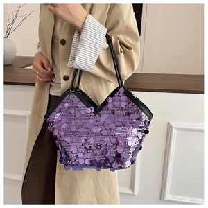 Detailed view of shimmering purple sequin tote bag with black handles on a model