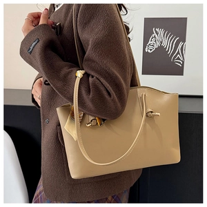 Close-up of khaki tote bag featuring knotted strap and elegant silk scarf detail