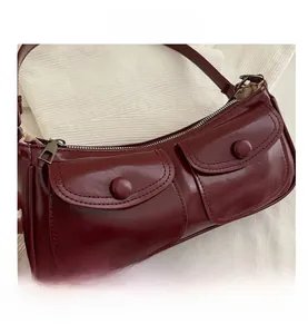 Détail d'un sac baguette bordeaux avec deux poches et une finition en cuir brillant