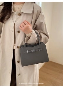 Detail of dark grey leather tote bag with silver metal lock and refined pebble texture