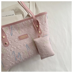 Detail of light pink tote bag set showing embossed texture and wavy colorful embroidery