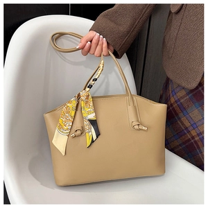 Detail of beige tote bag handle with stylish patterned silk scarf and metal accents