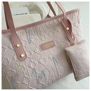 Close-up of pink tote bag showing quilted texture, colorful embroidery, and gold rivets