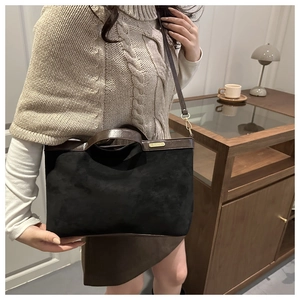 Detail of matte black suede and brown leather contrast on stylish shoulder handbag