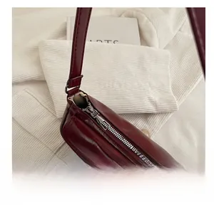 Détail de la fermeture éclair en métal argenté sur un sac porté épaule rouge vin