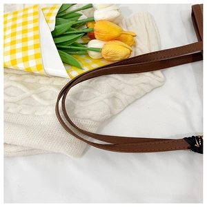 Detail of brown leather strap with precise stitching on a minimalist shoulder bag